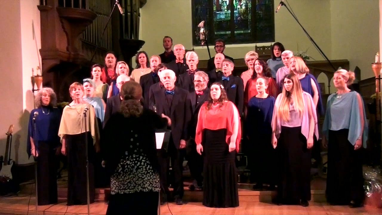 The choir in coloured shawls of red, blue, gold and lilac, with Kim Kleineberg conducting from the front.